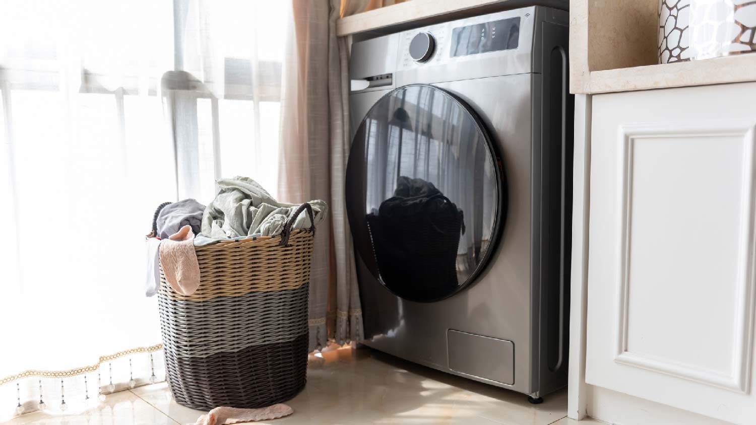 A basket with laundry in front of a dryer