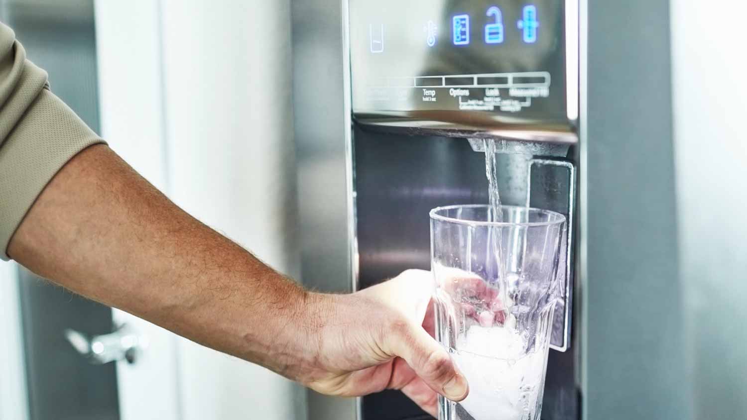 man filling glass from refrigerator