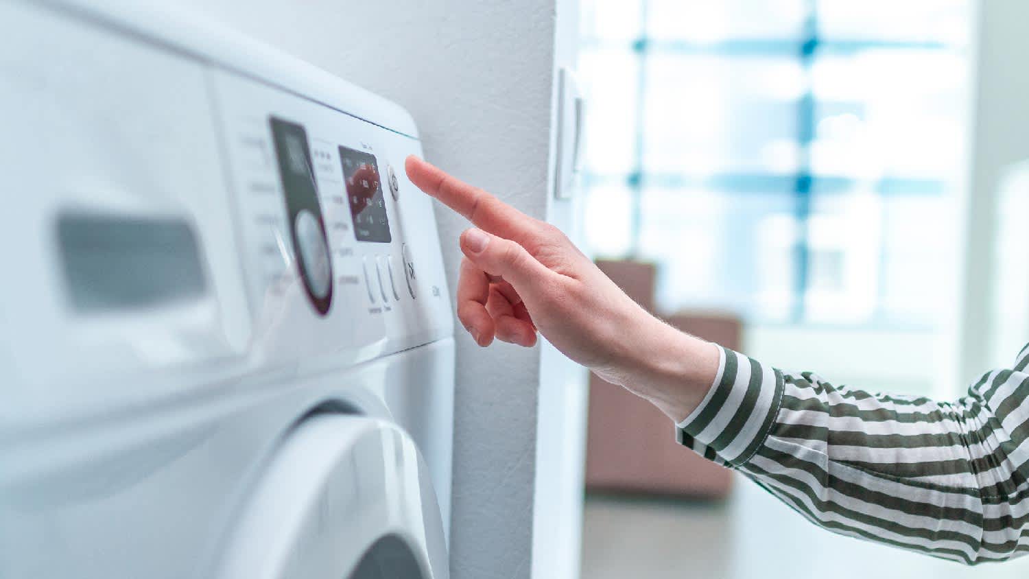 A woman turning on the dryer