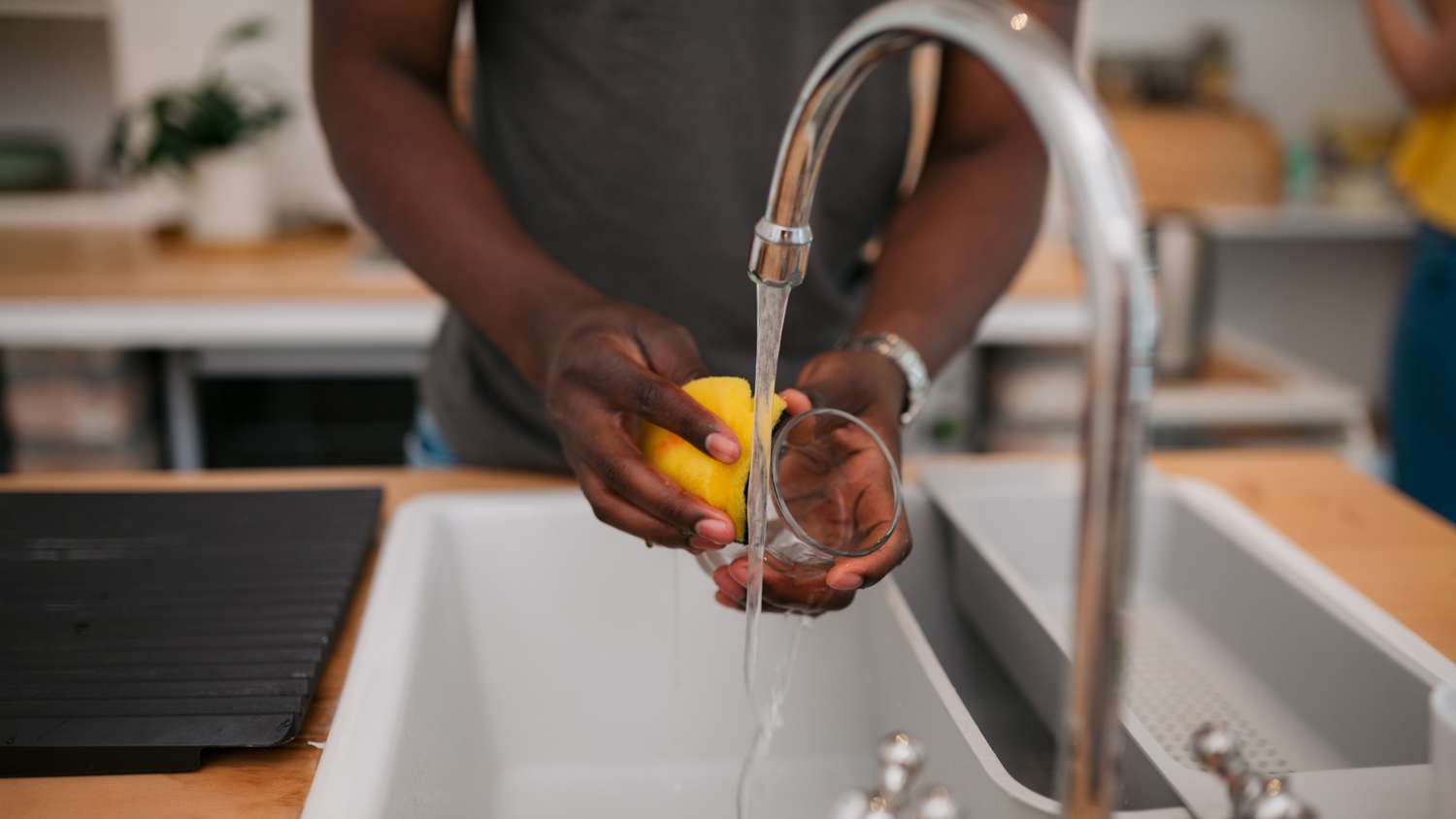 Close-up of young man washing a glass in sink at home