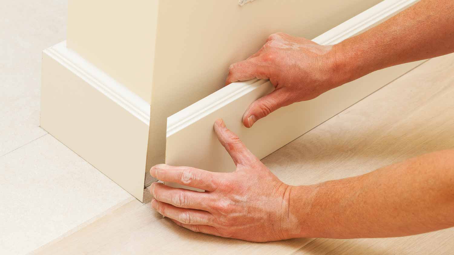 Man installing wooden trim on wall