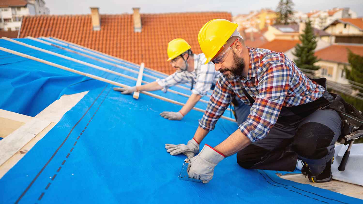 Roofers installing synthetic roof underlayment