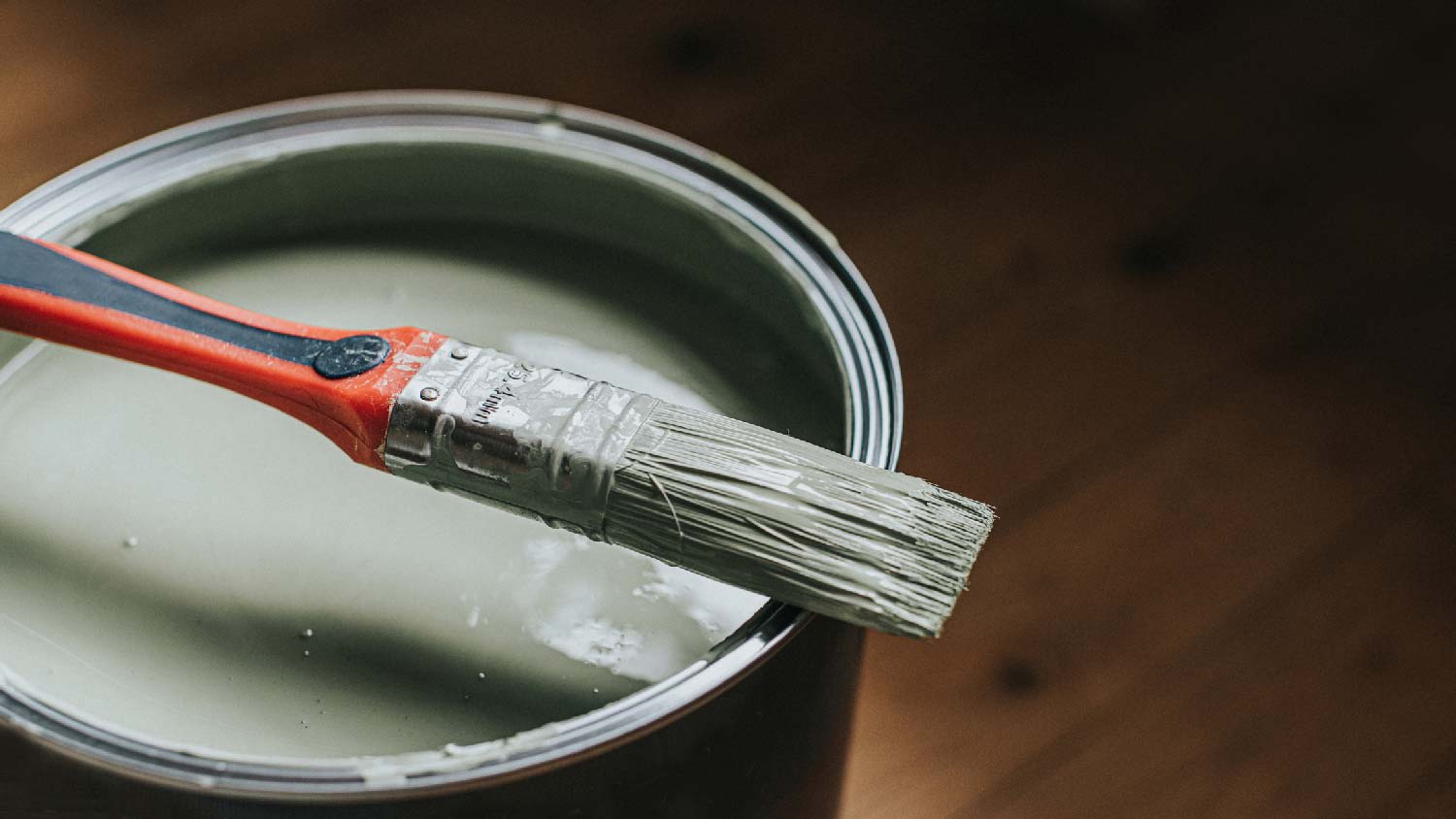 Close-up of a bucket of eggshell paint with a brush