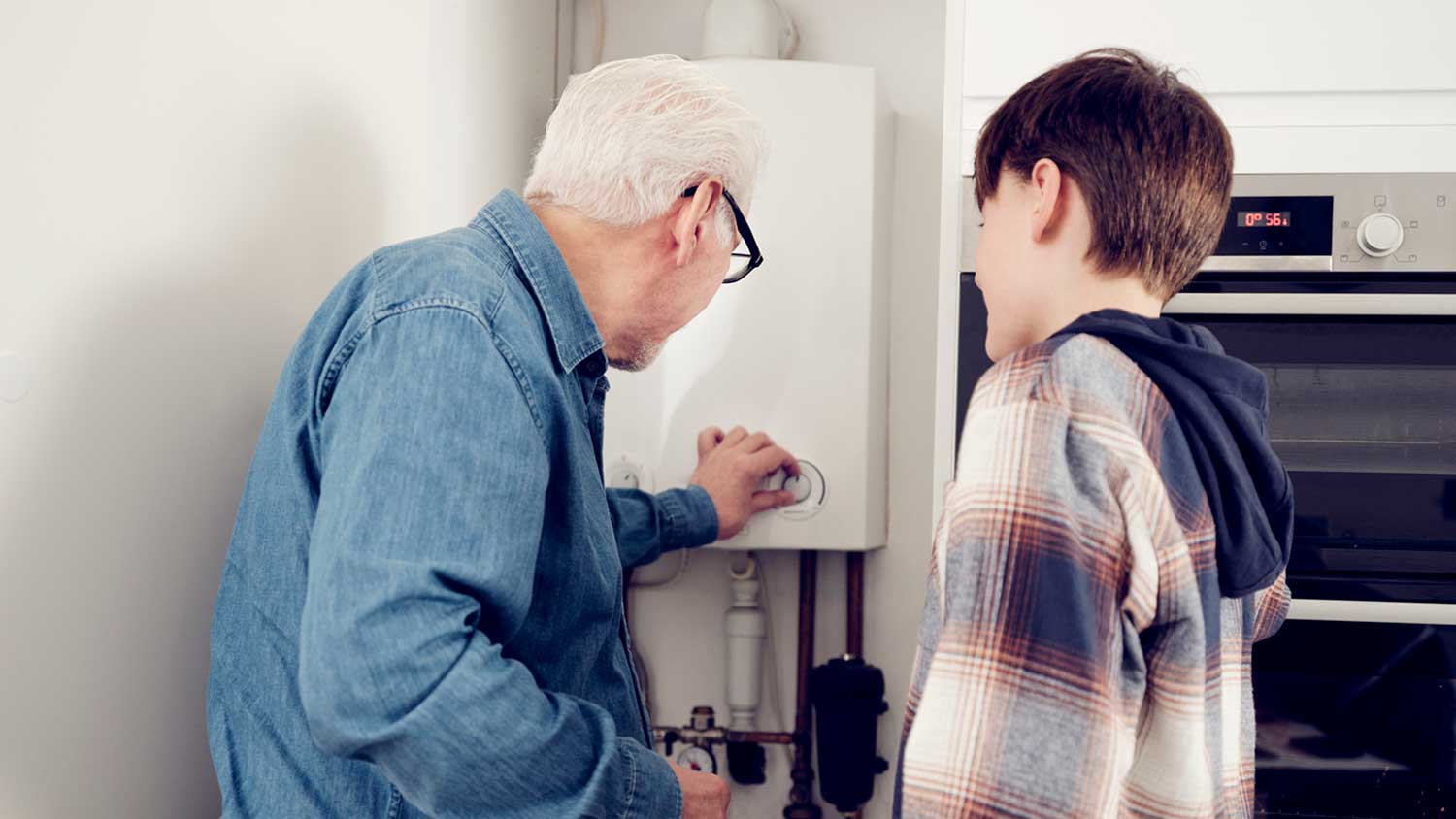 Grandpa and grandson adjusting water heater temperature