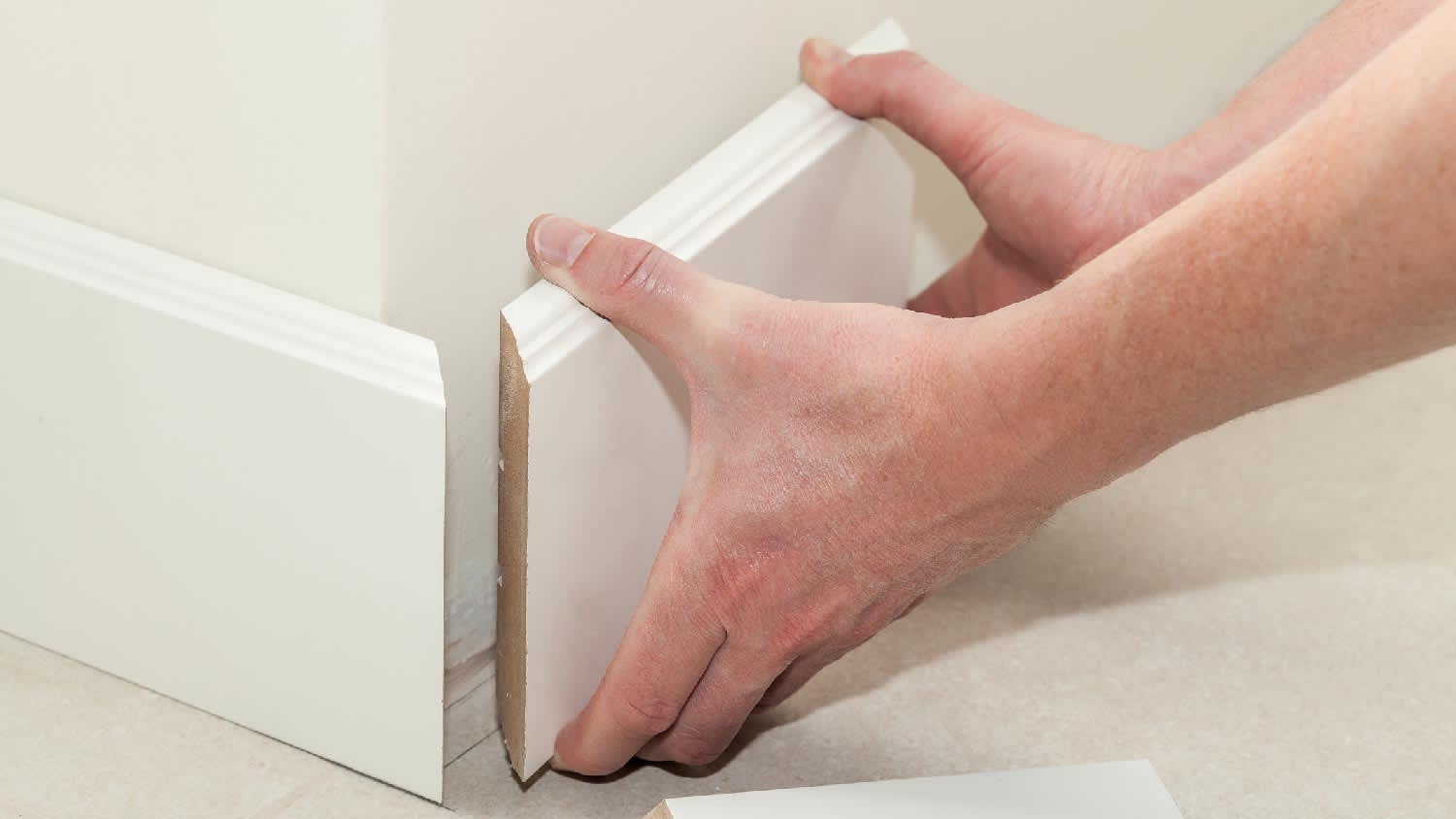 Close-up of a person installing a baseboard