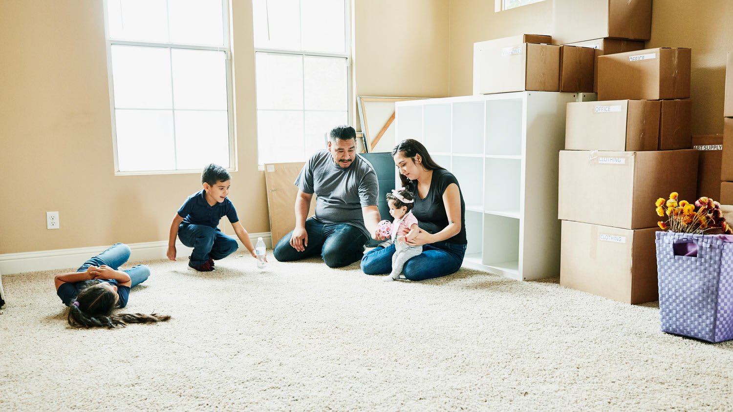 Family sitting on floor of living room of new home during move in day