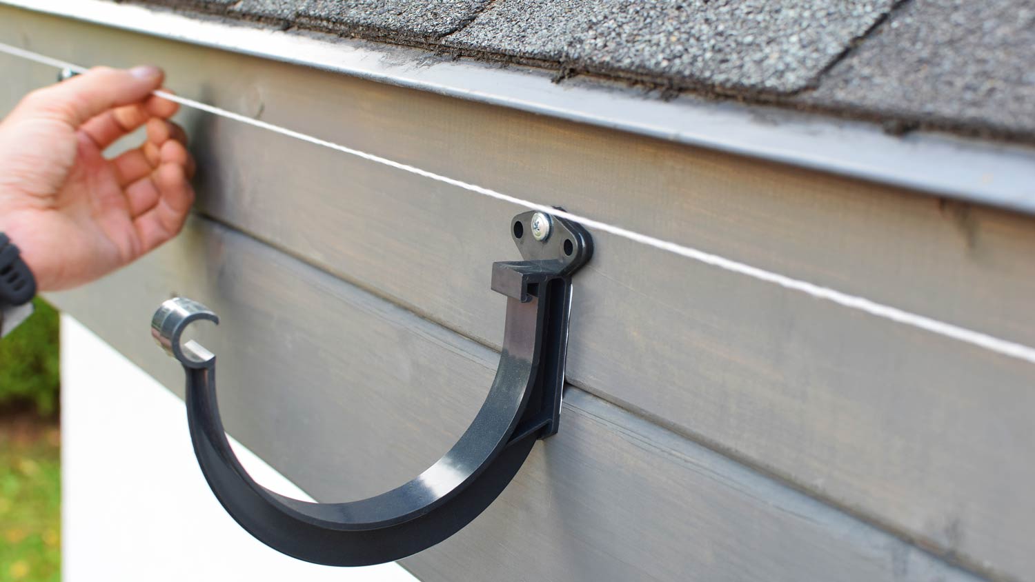 man measuring gutter with string