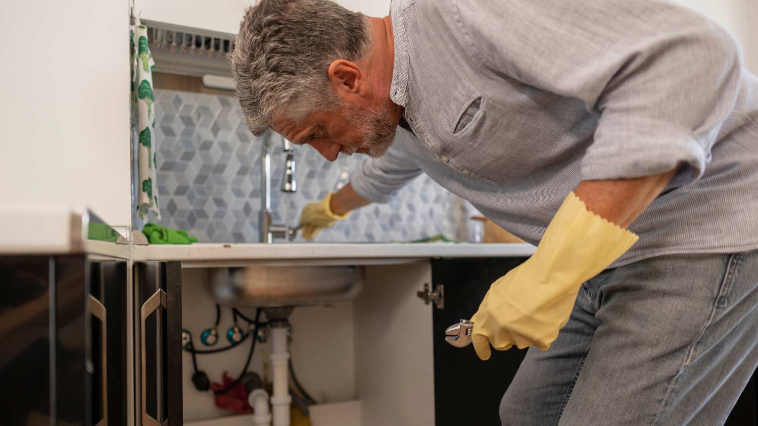 man repairing kitchen faucet