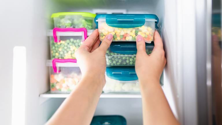Woman taking frozen food out of freezer