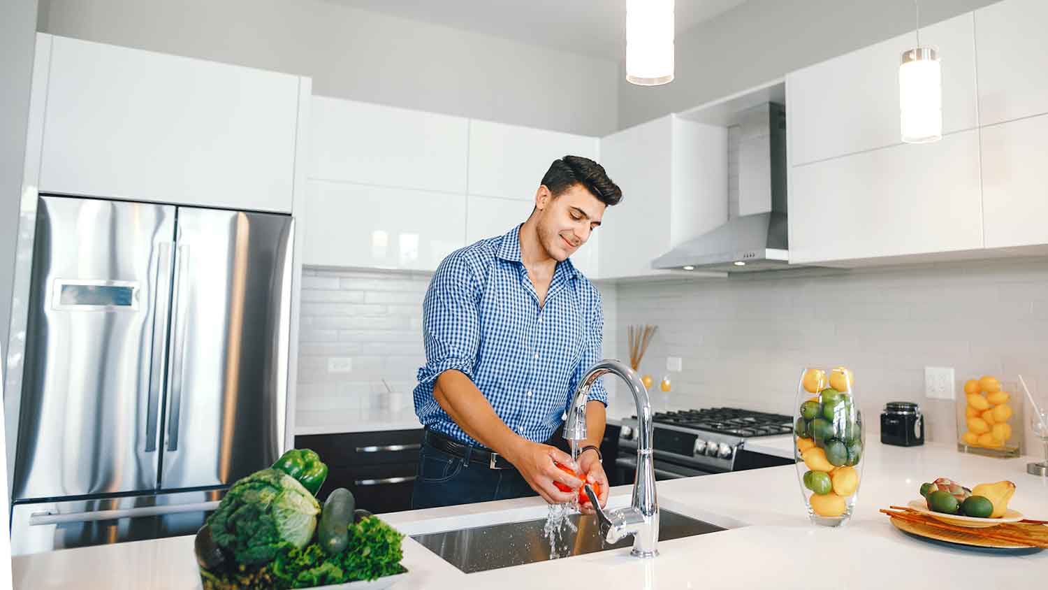 Man washing veggies in the kitchen sink