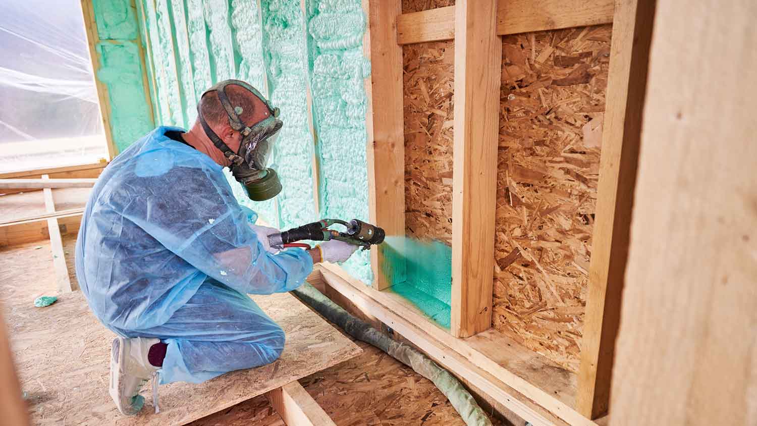 Worker at construction site is spraying polyurethane foam insulation