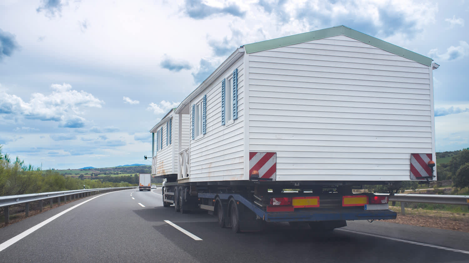 Driving behind heavy-duty truck carrying two prefabricated houses