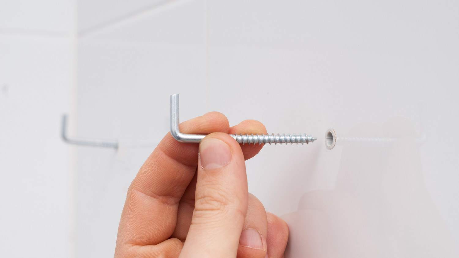 A person attaching mounting hooks to a wall