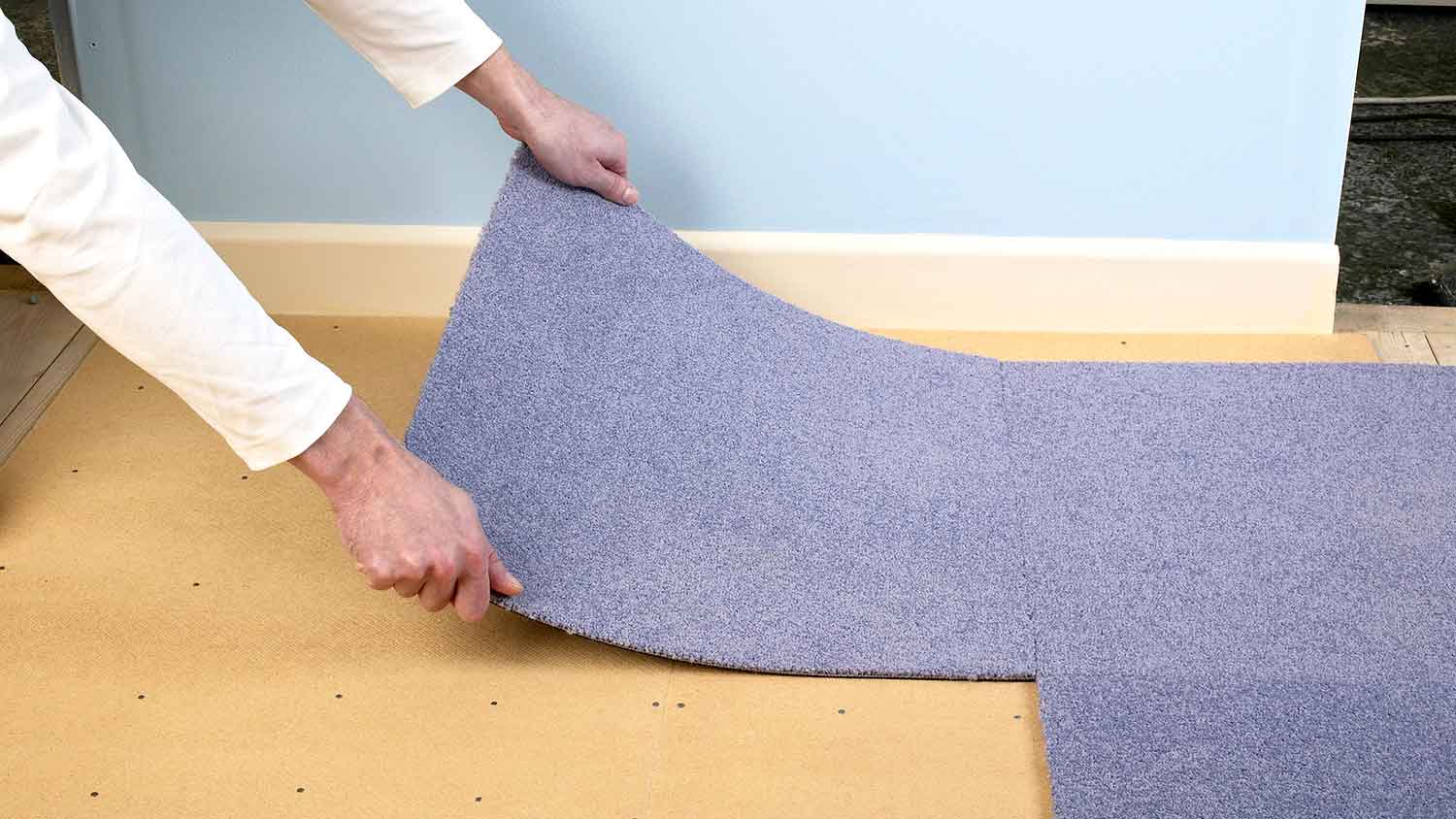 Worker installing carpet tiles in the room