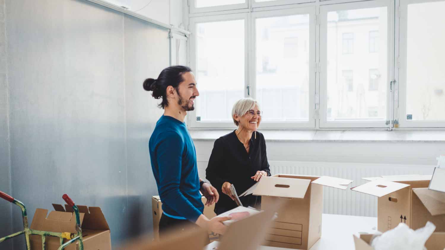 Woman and colleague unpacking cardboard boxes