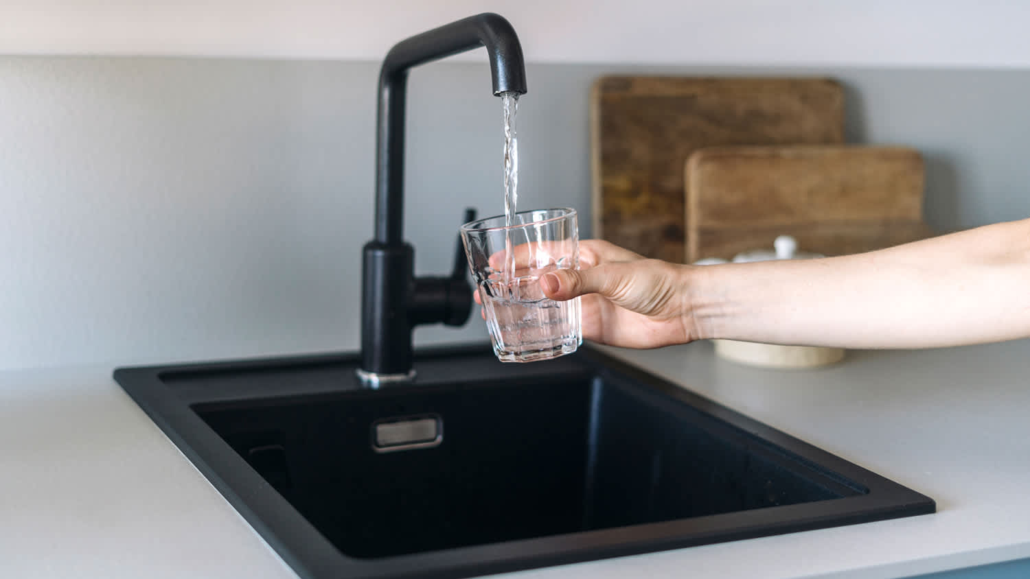 Hand holding glass near black sink
