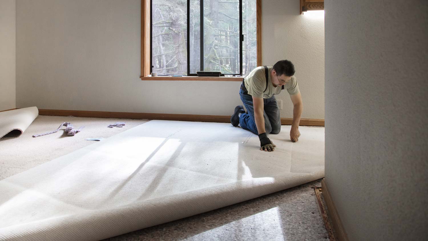 man installing carpet in room