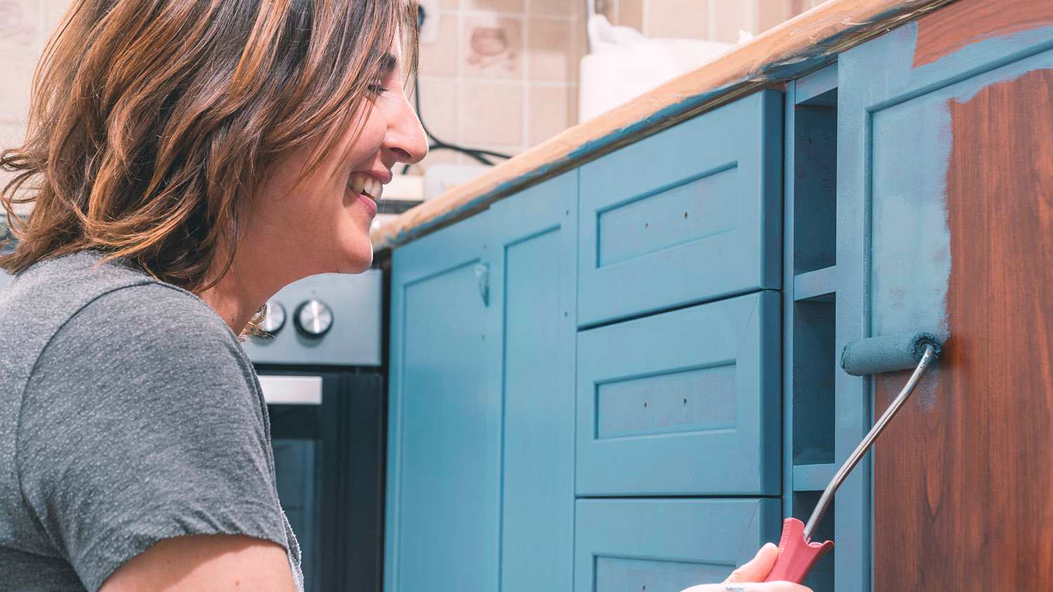 woman repainting old kitchen cabinets