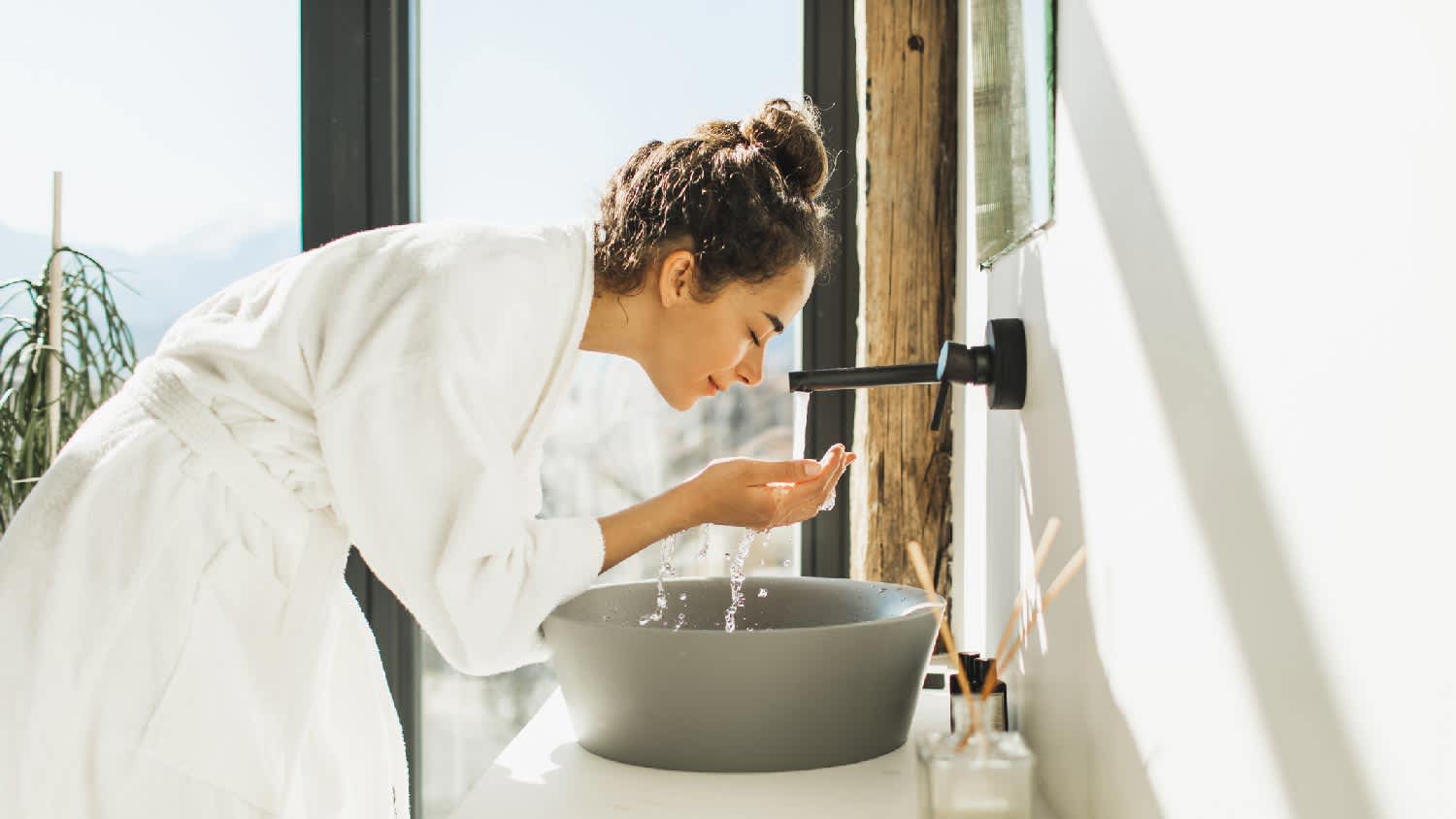 A woman washing her face in the bathroom sink