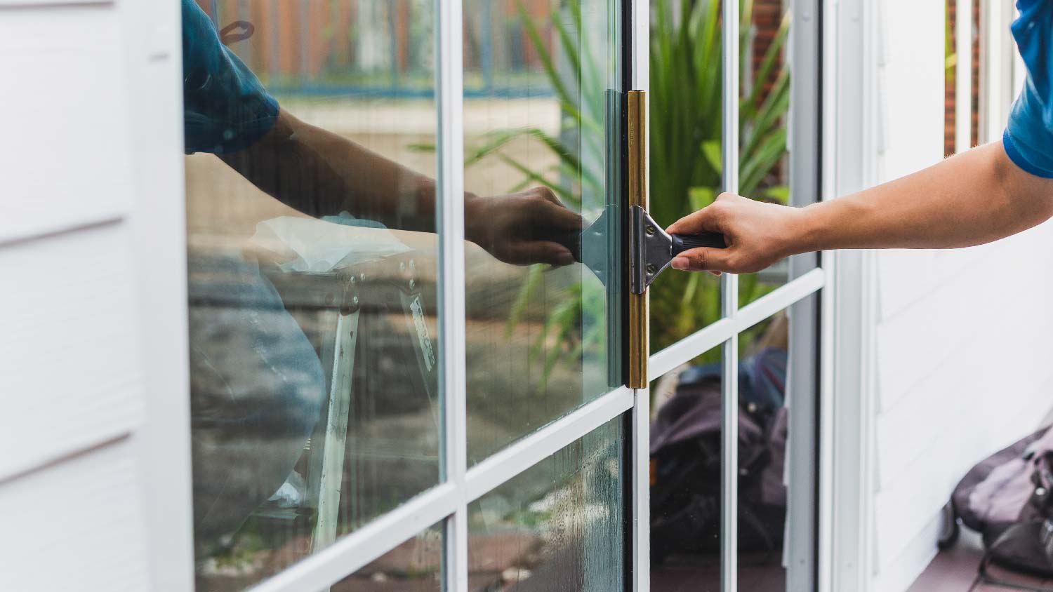 A person cleaning a tinted glass door