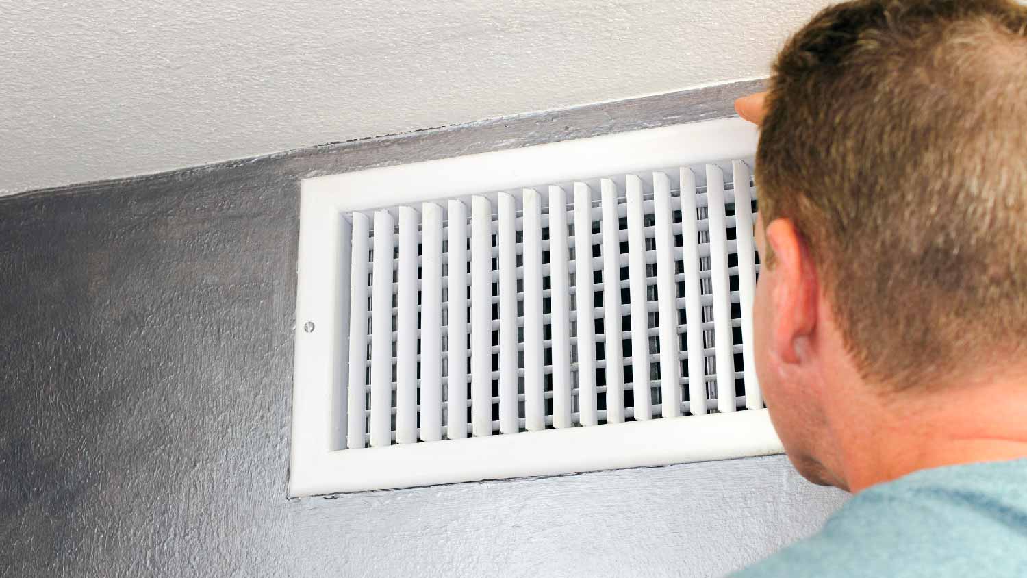 A man checking the air vent