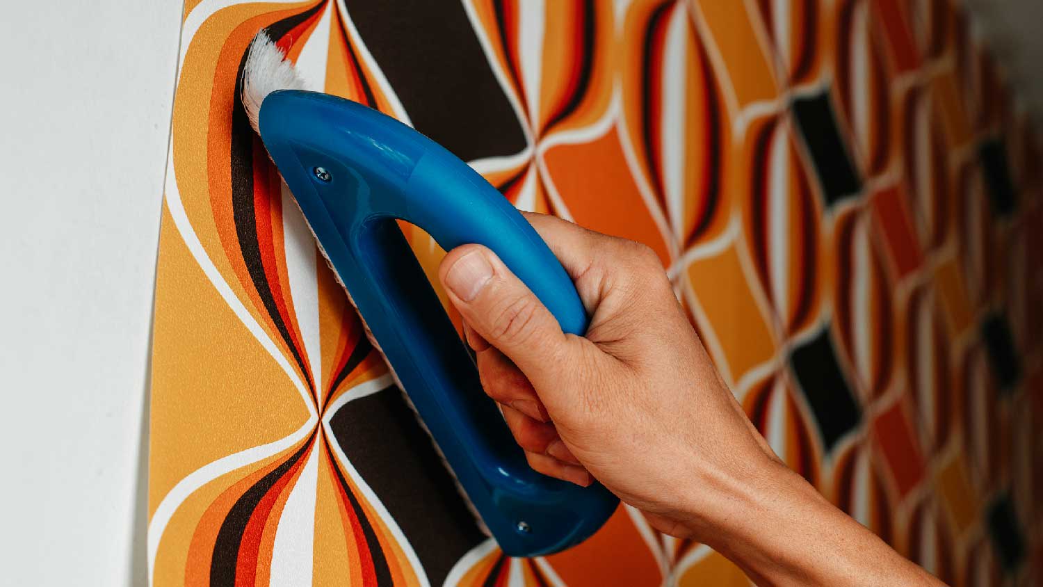Close-up of a person applying wallpaper on a wall with a brush