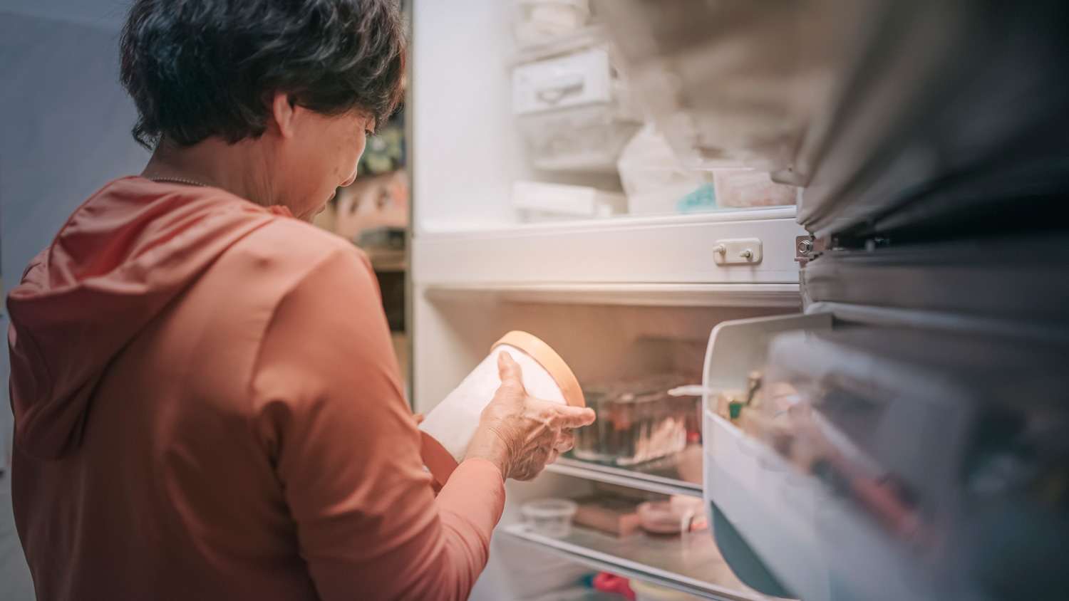 A senior woman taking ice cream out of the freezer