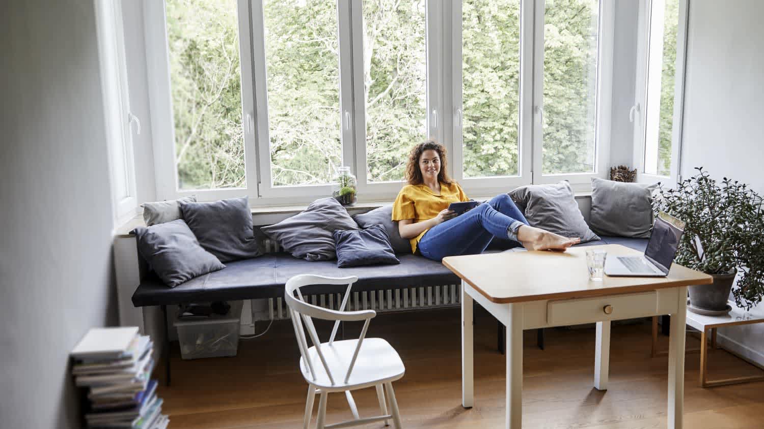 Woman relaxing on sofa against window at home