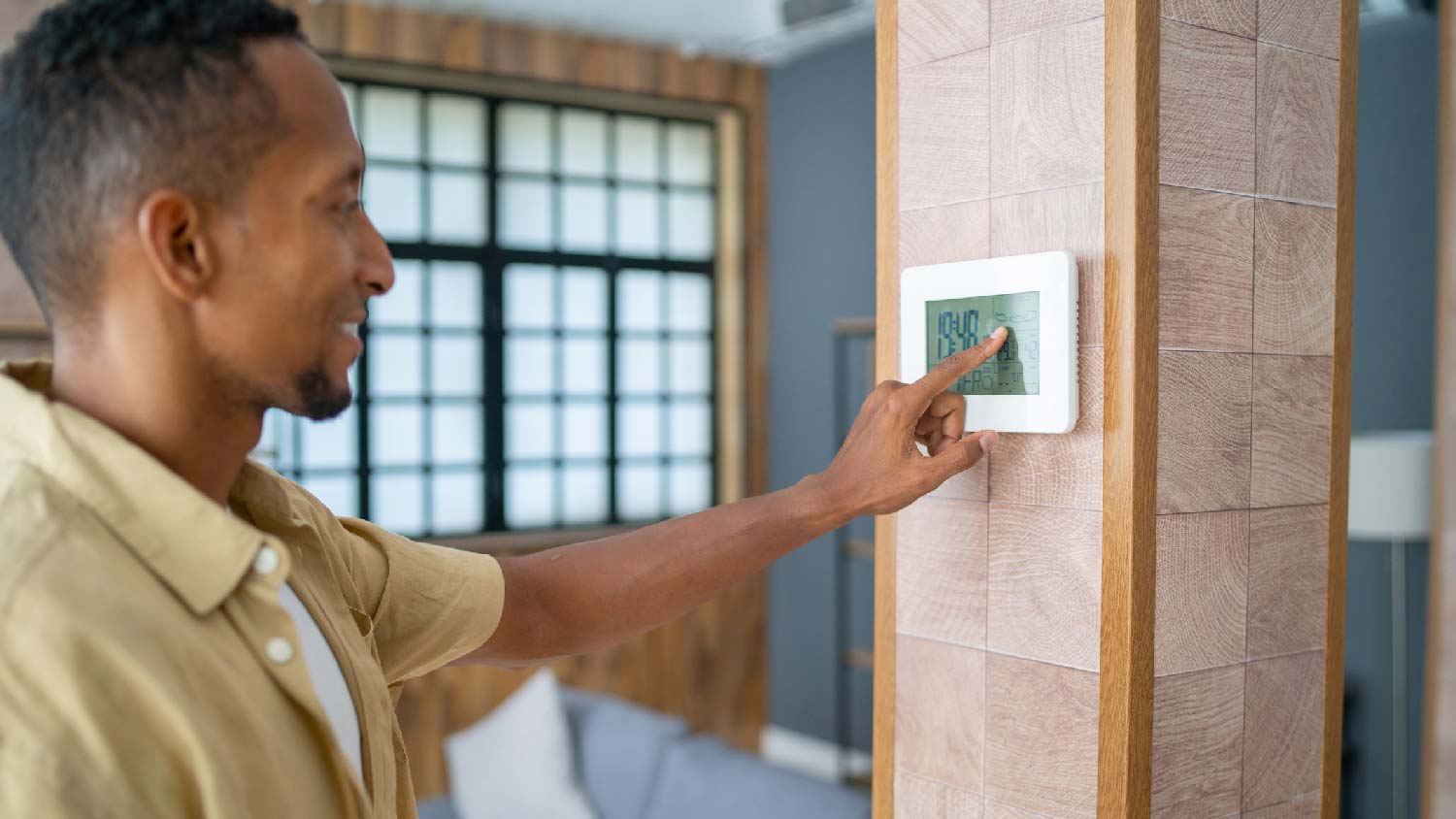 man adjusting thermostat in house