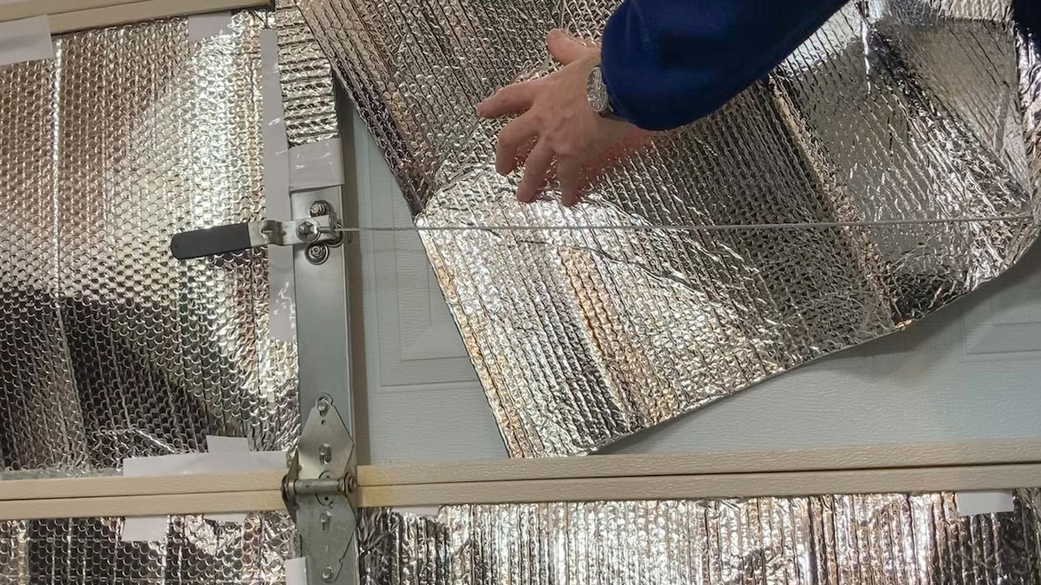 A person insulating the interior of a garage with reflective foil