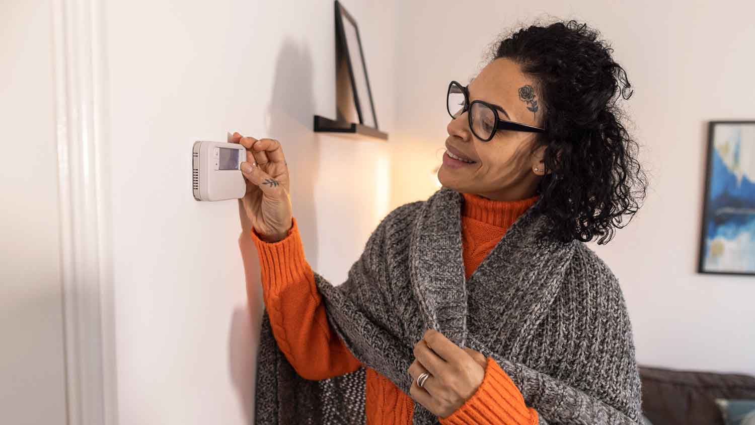 Woman adjusting thermostat in the room