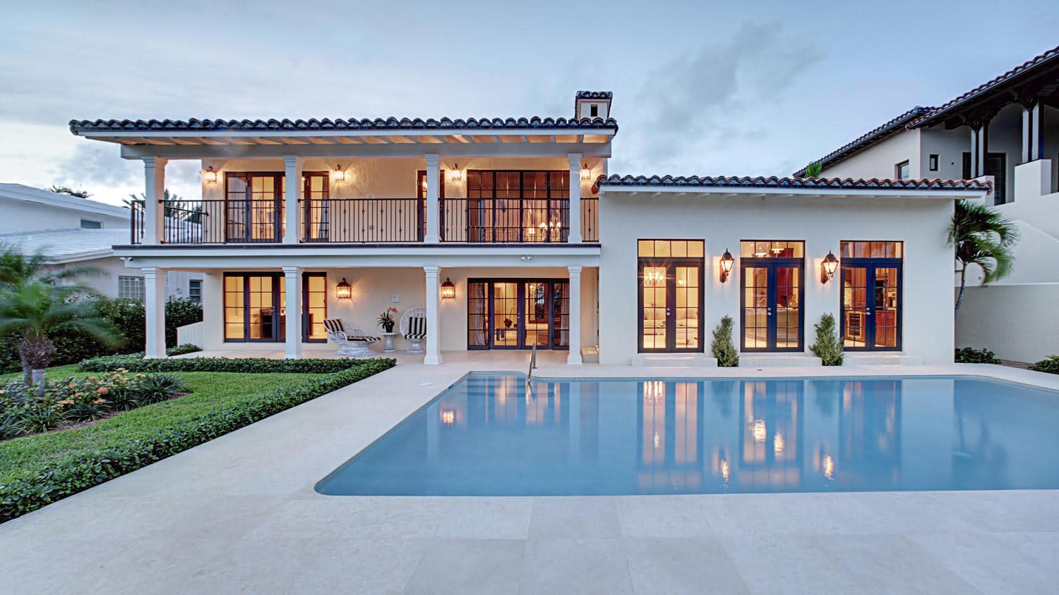 The exterior of a beautiful house with a pool at dusk