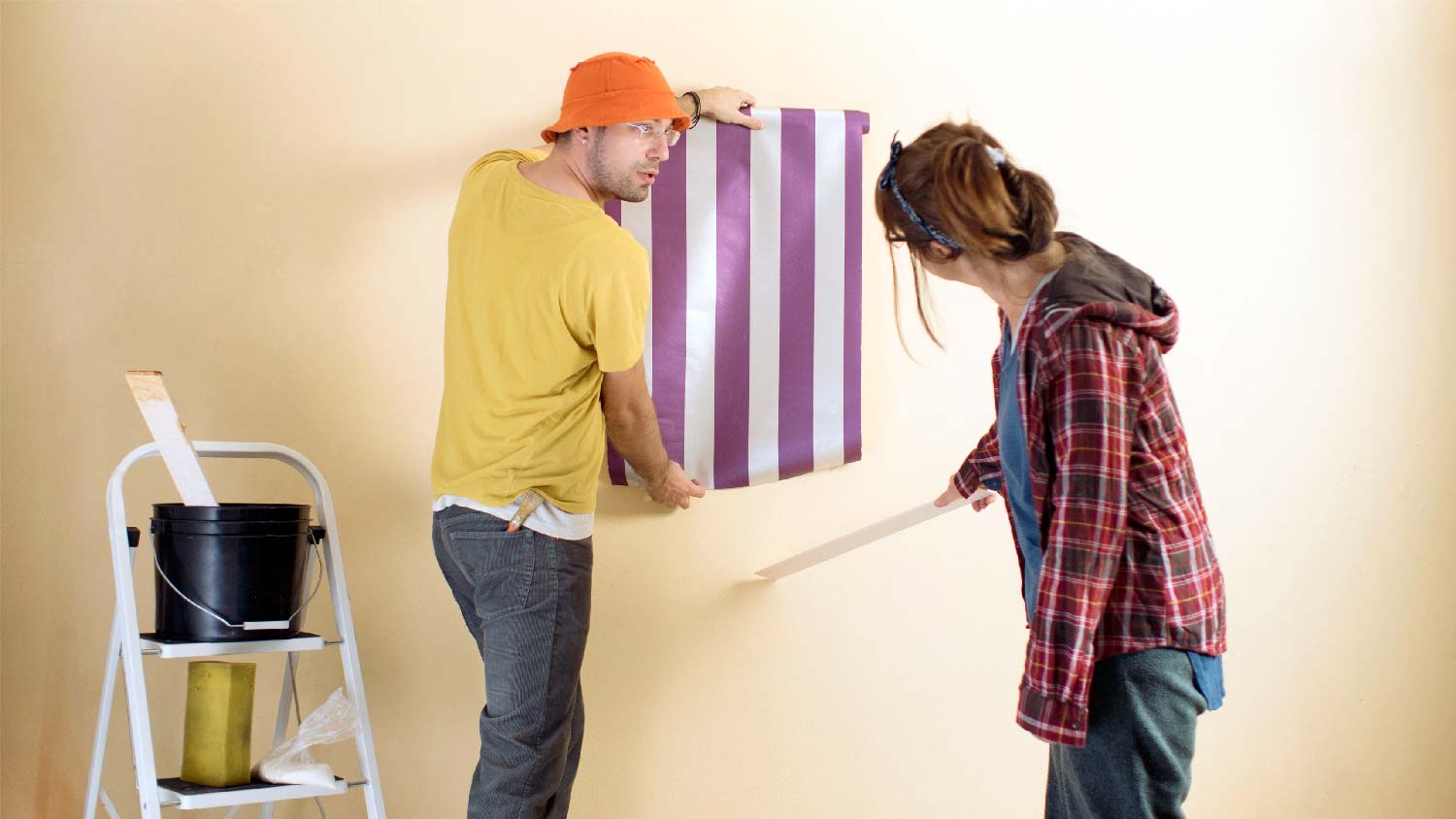 A couple testing a wallpaper on a wall