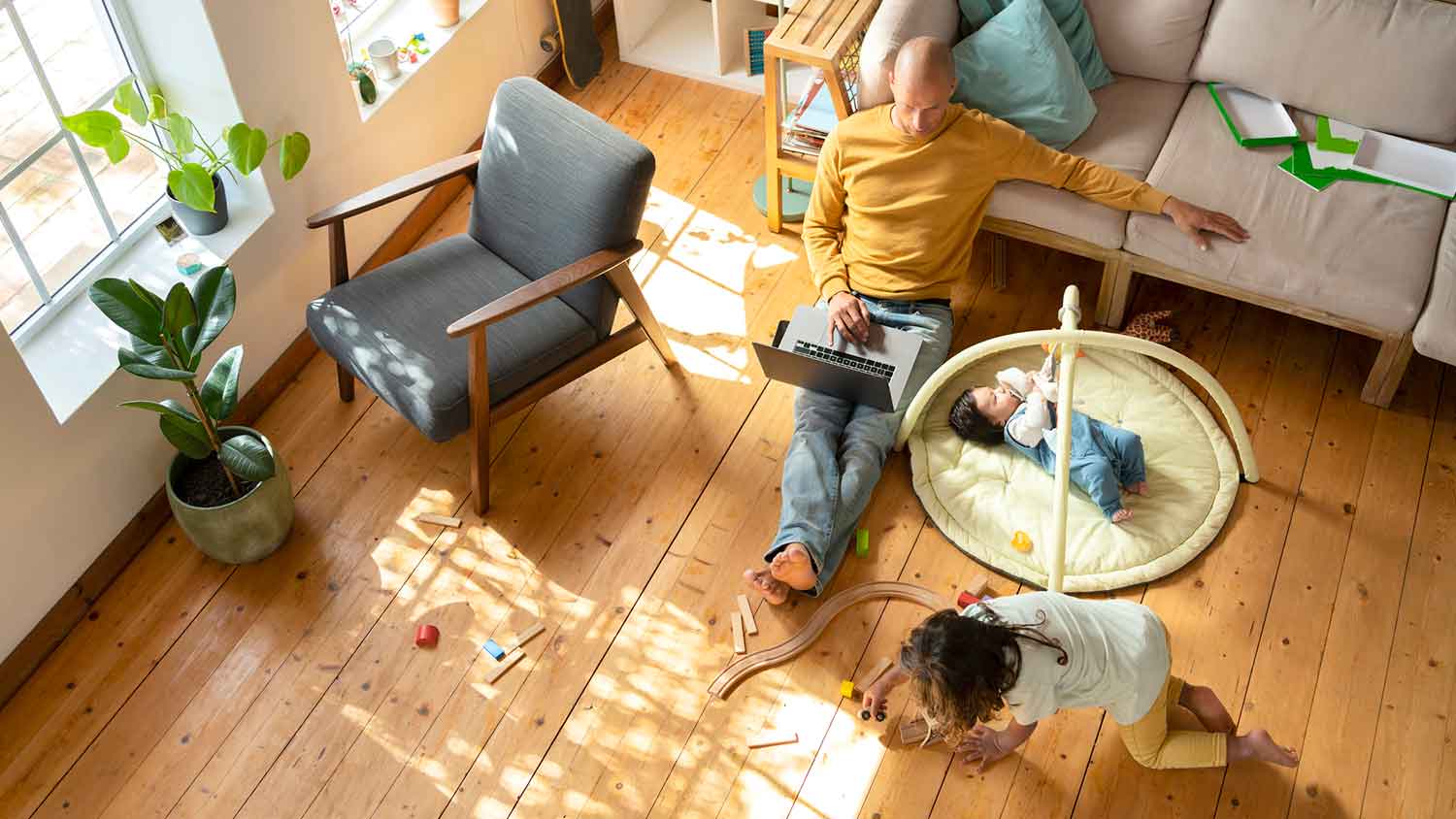 Father sitting on a hardwood floor working from home