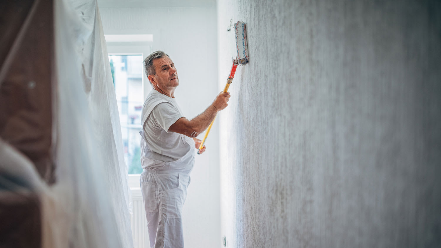 Worker painting wall using a roller