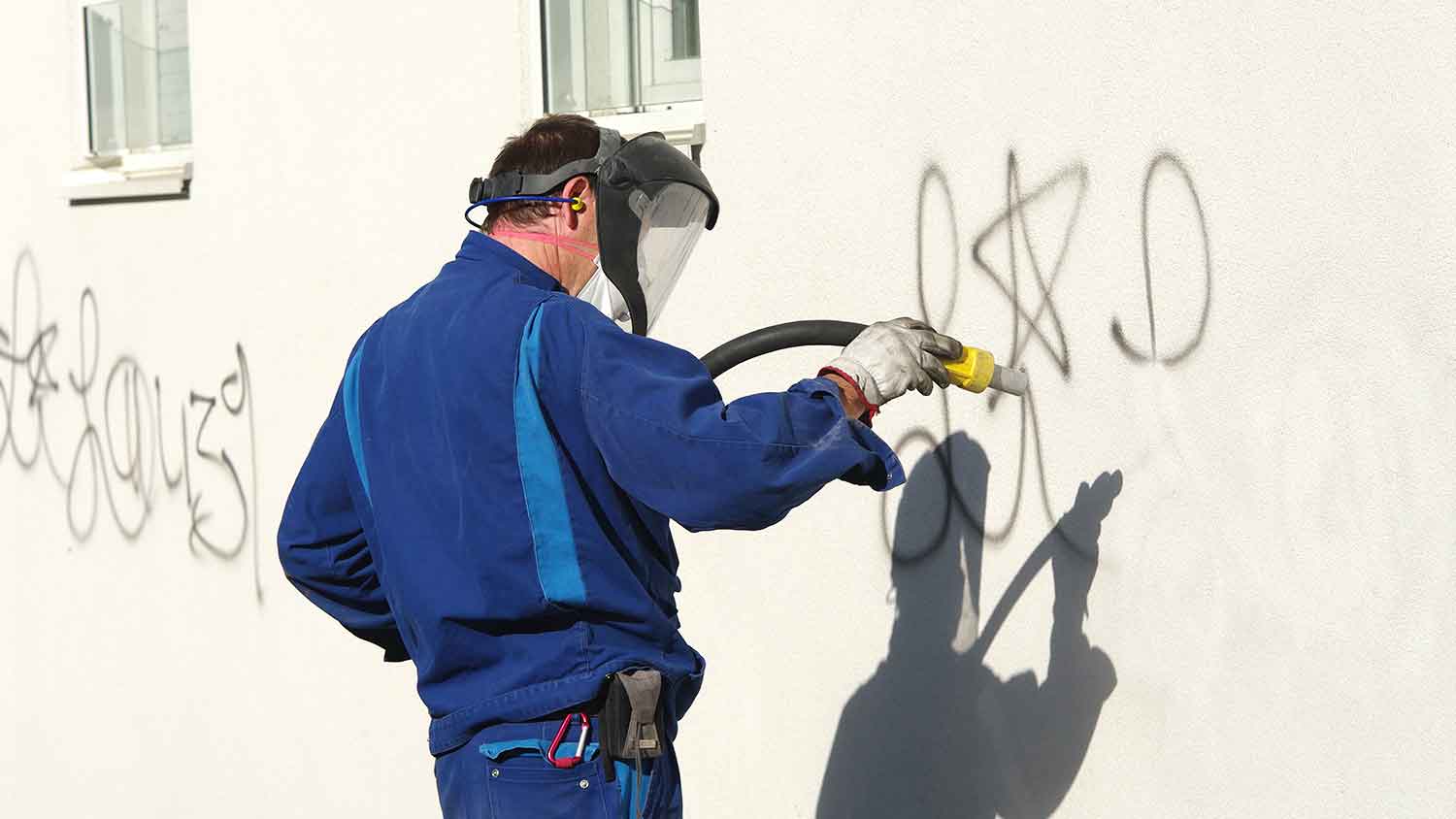 Man using soda blasting to remove graffiti from the wall