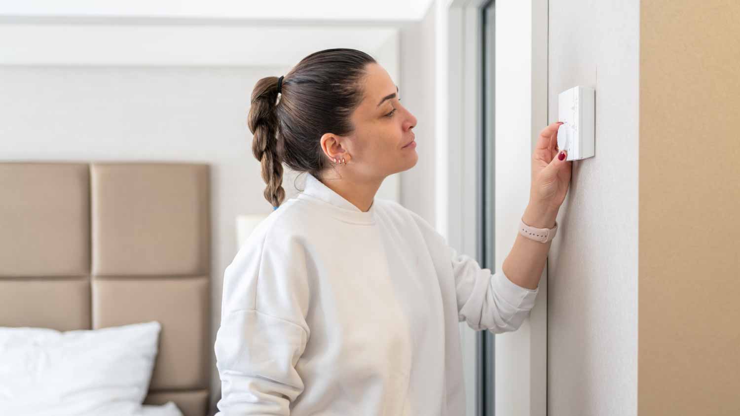 Woman setting temperature on air conditioner