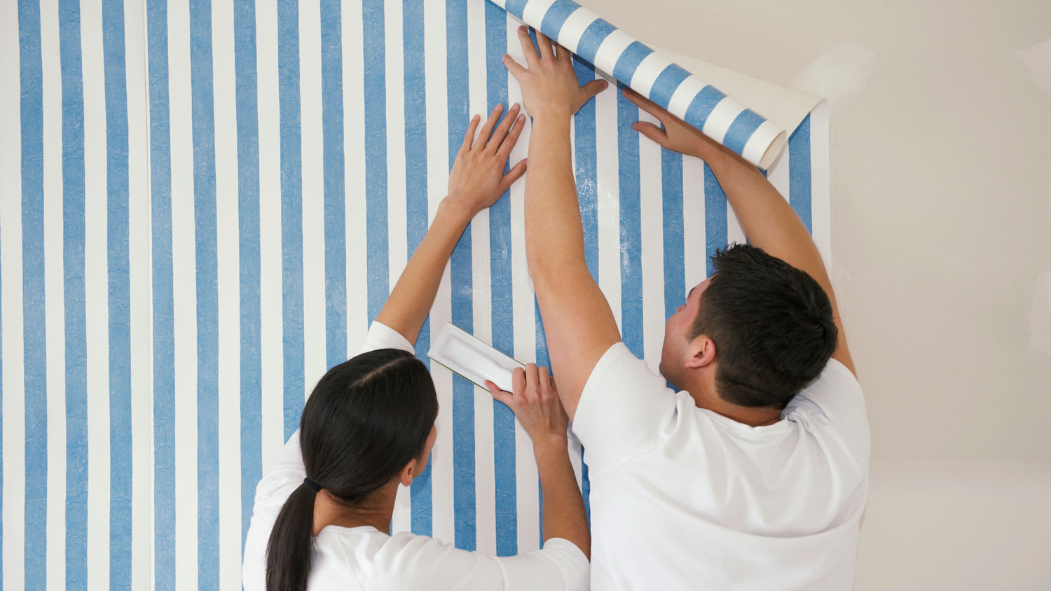A couple putting up a wallpaper