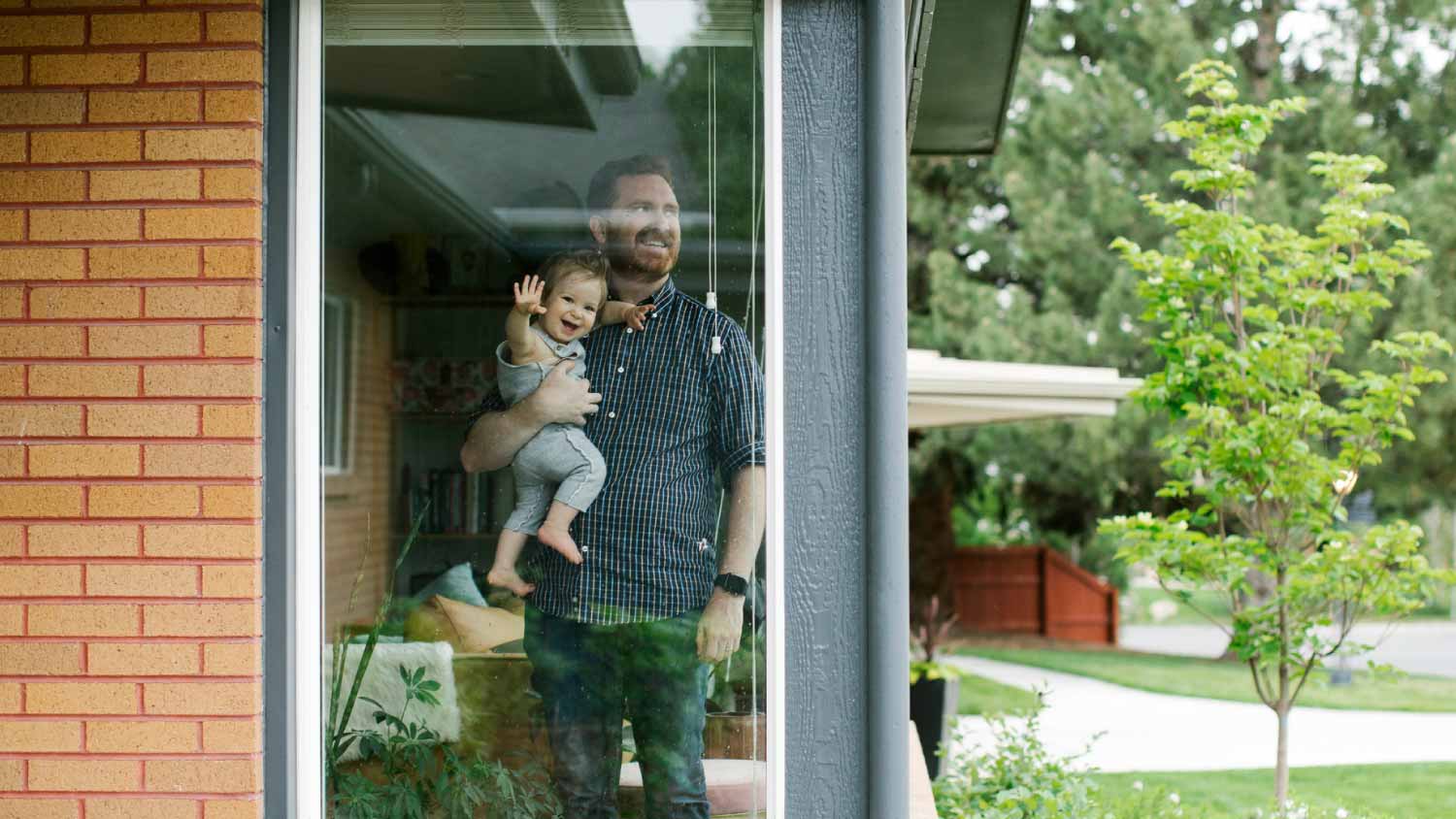 Father holding his daughter behind window