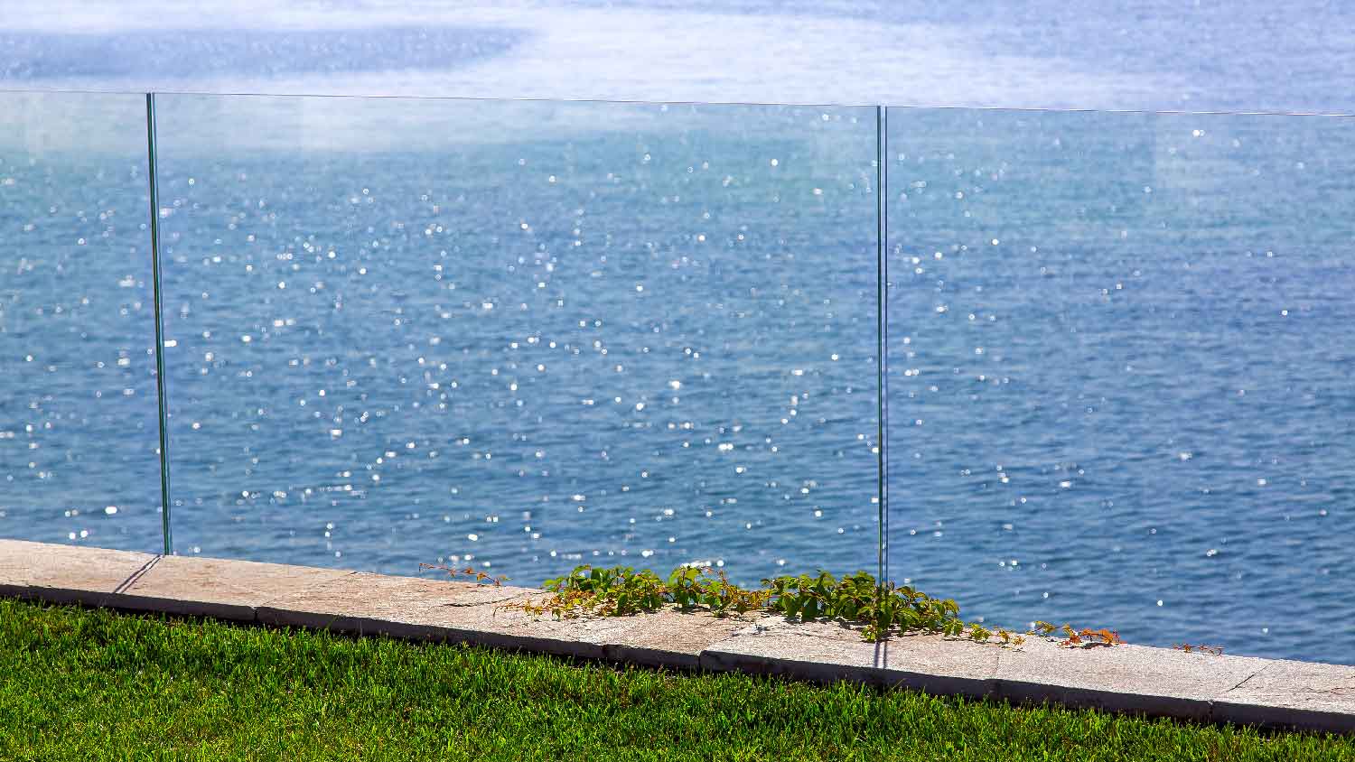 A garden with a glass fence and magnificent seaview
