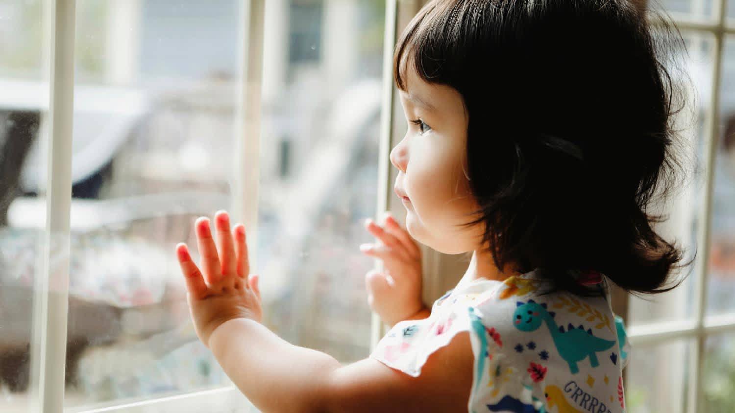 A toddler looking out a window with grids