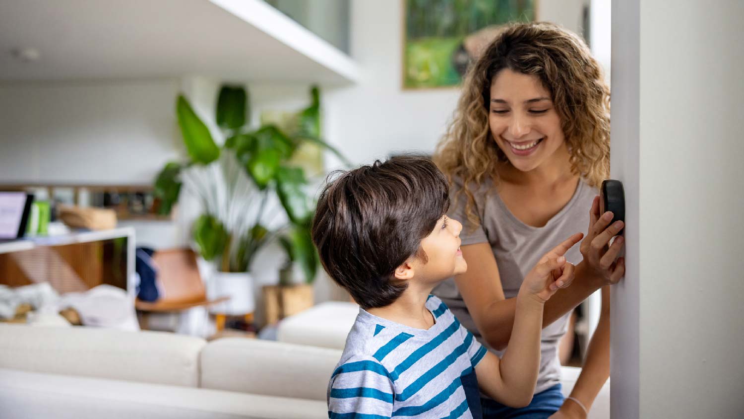 A mother and her son adjusting the thermostat