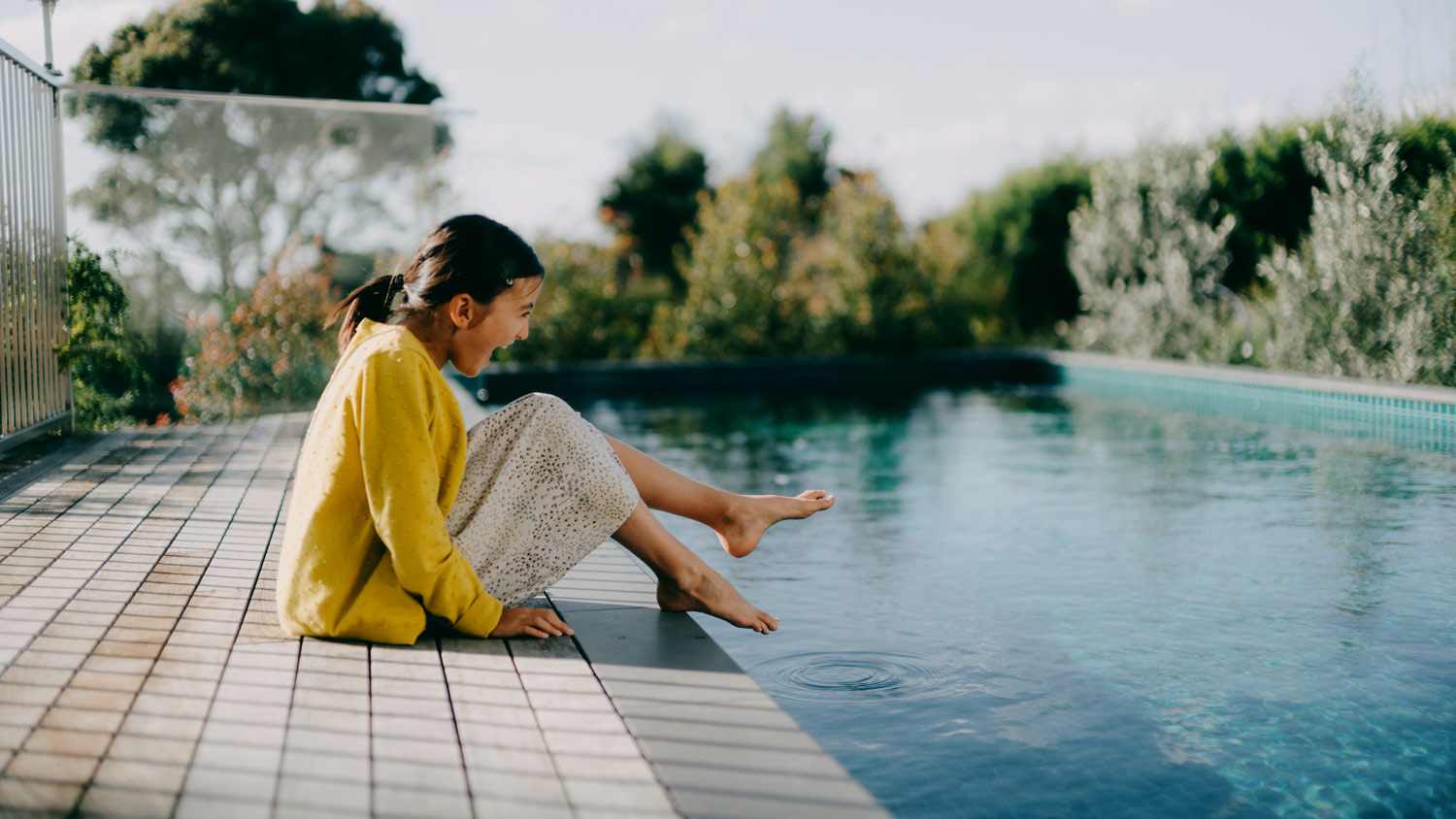 Young girl sitting by pool at home