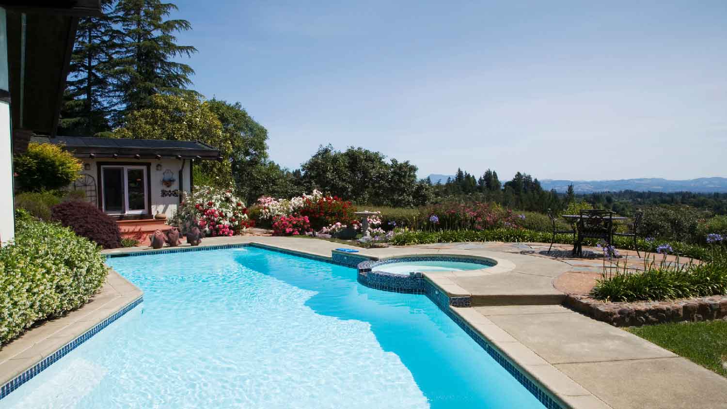 A large pool with a hot tub build next to it