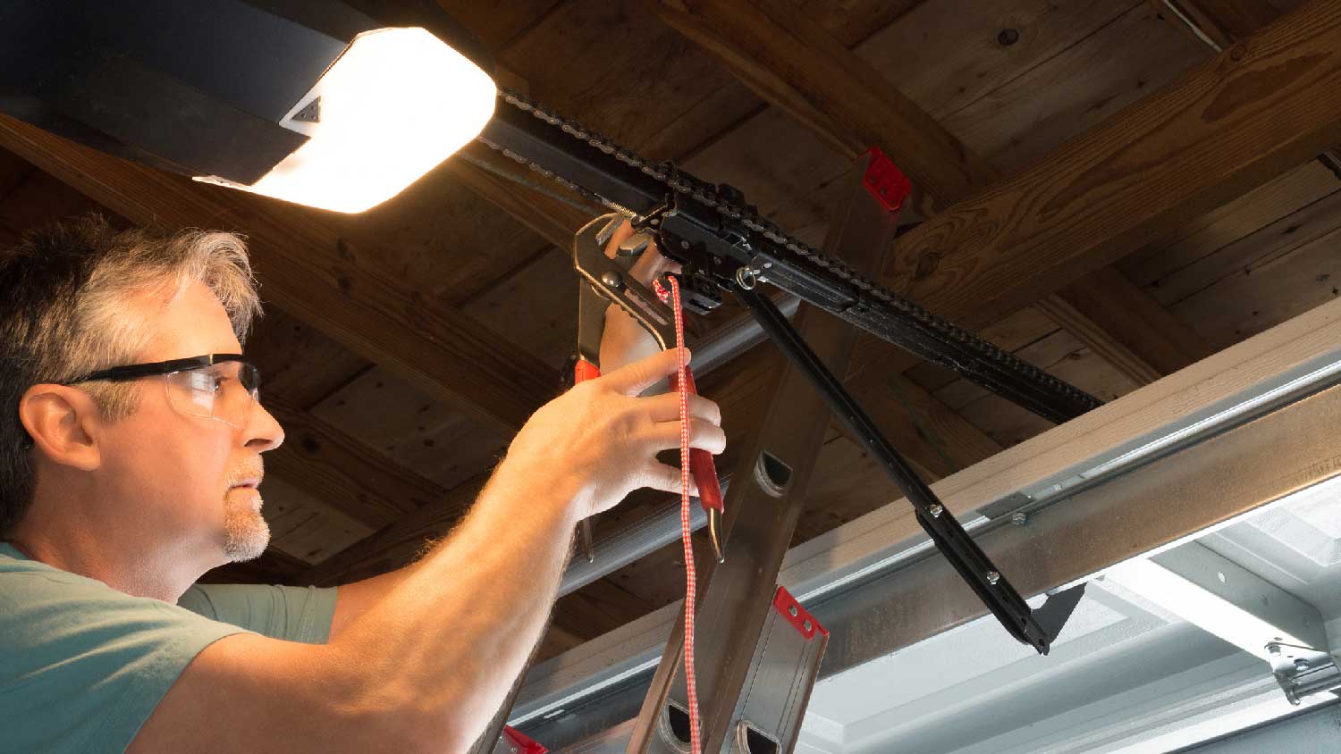 A man fixing a garage door cable