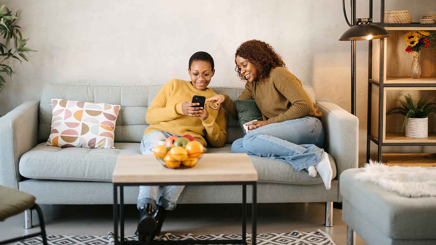 Couple sitting on the couch using phone to program smart thermostat