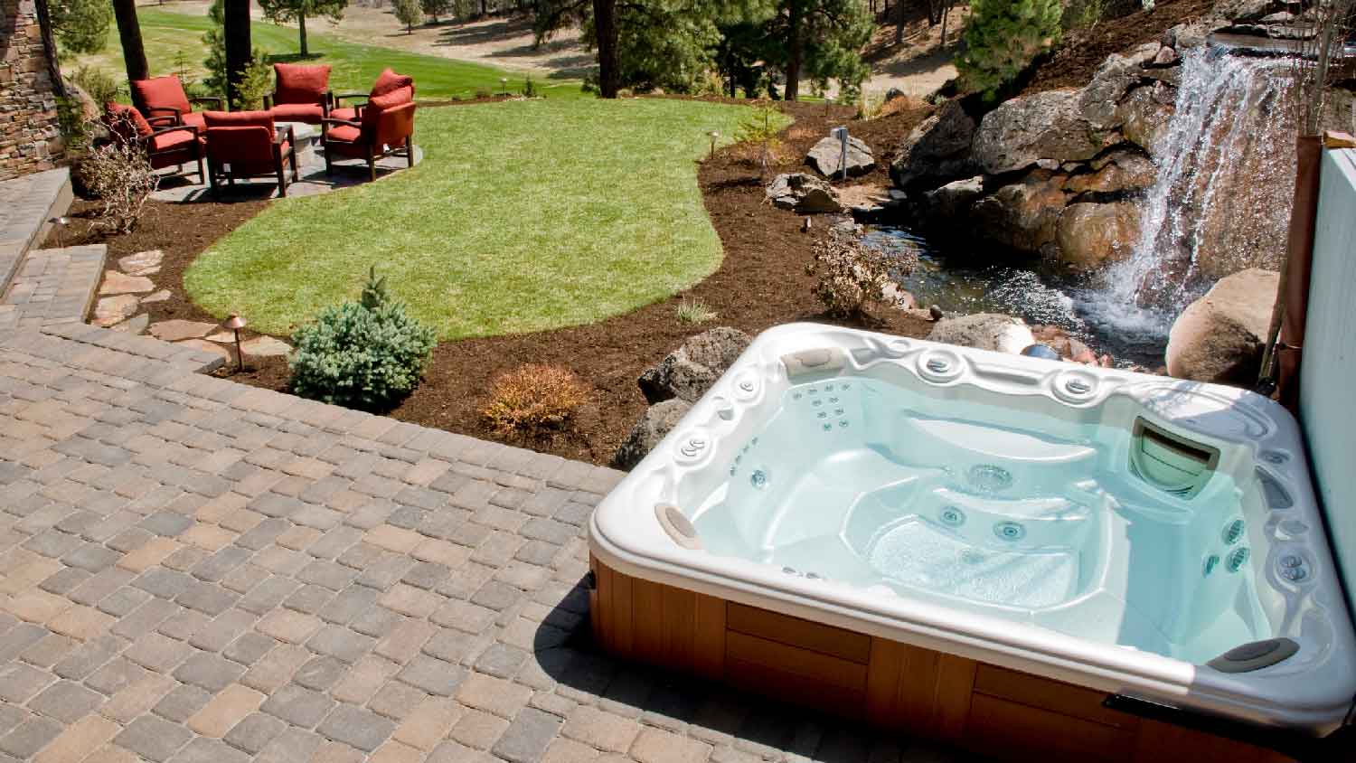 A hot tub in a backyard with a waterfall