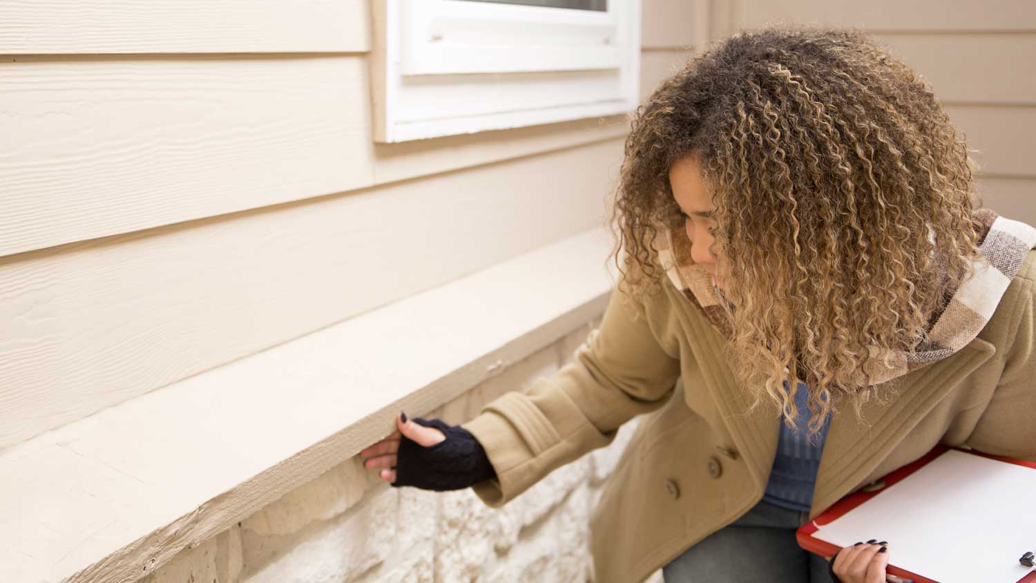 woman inspecting the outside of a home