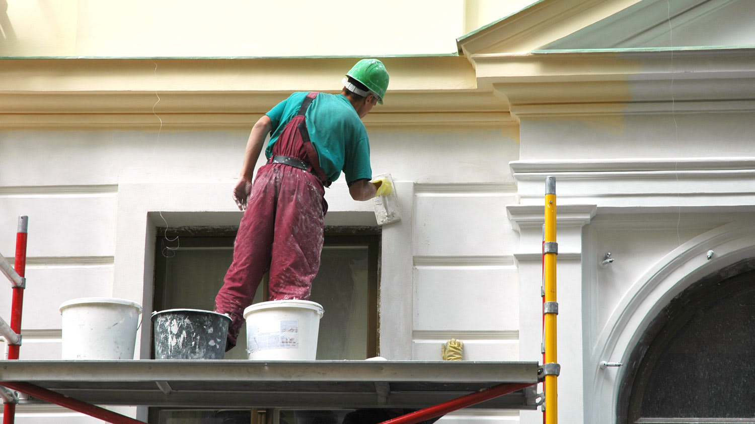 A worker sanding a wall