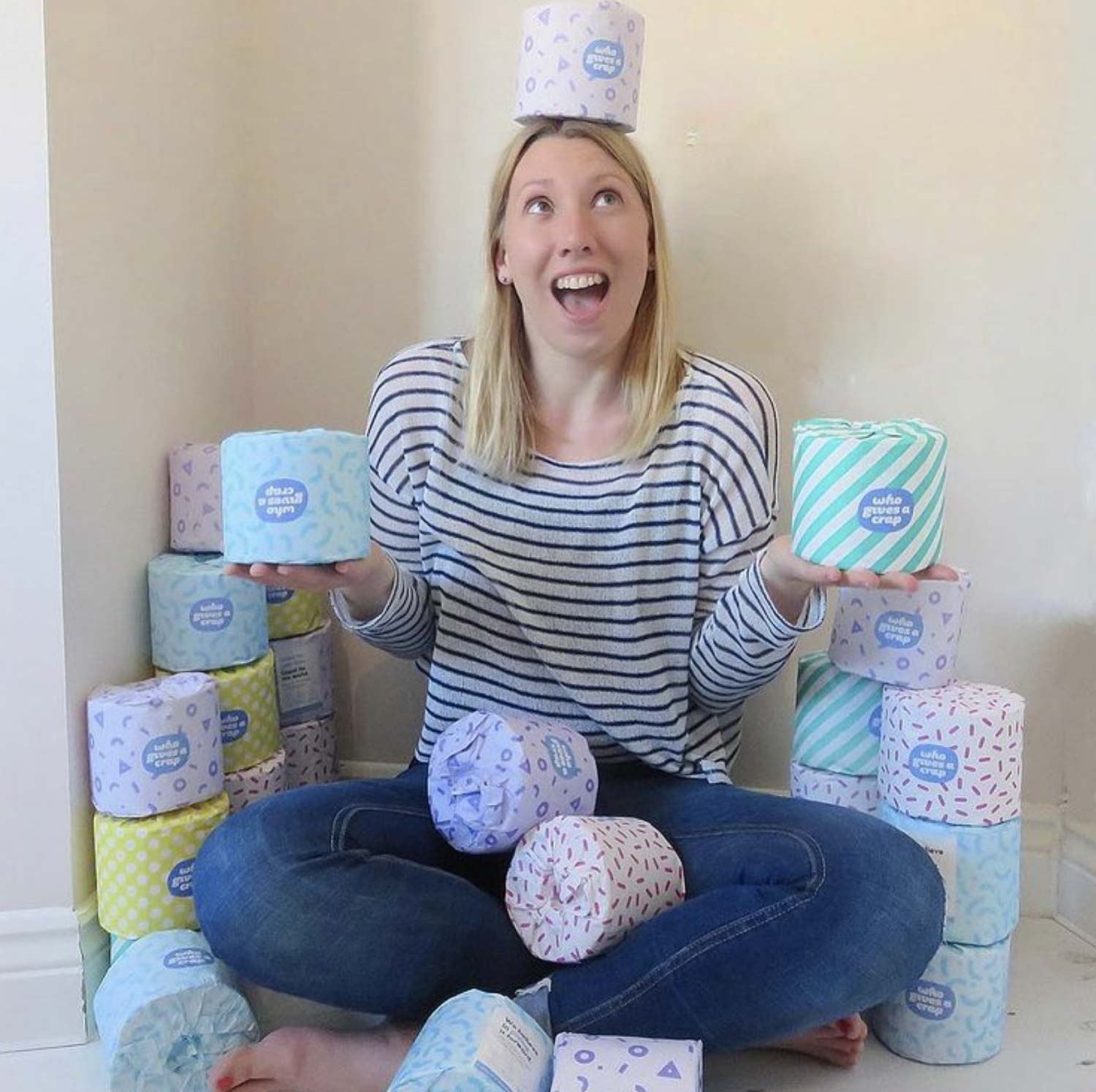 Emma Reed sitting on floor holding rolls of toilet paper